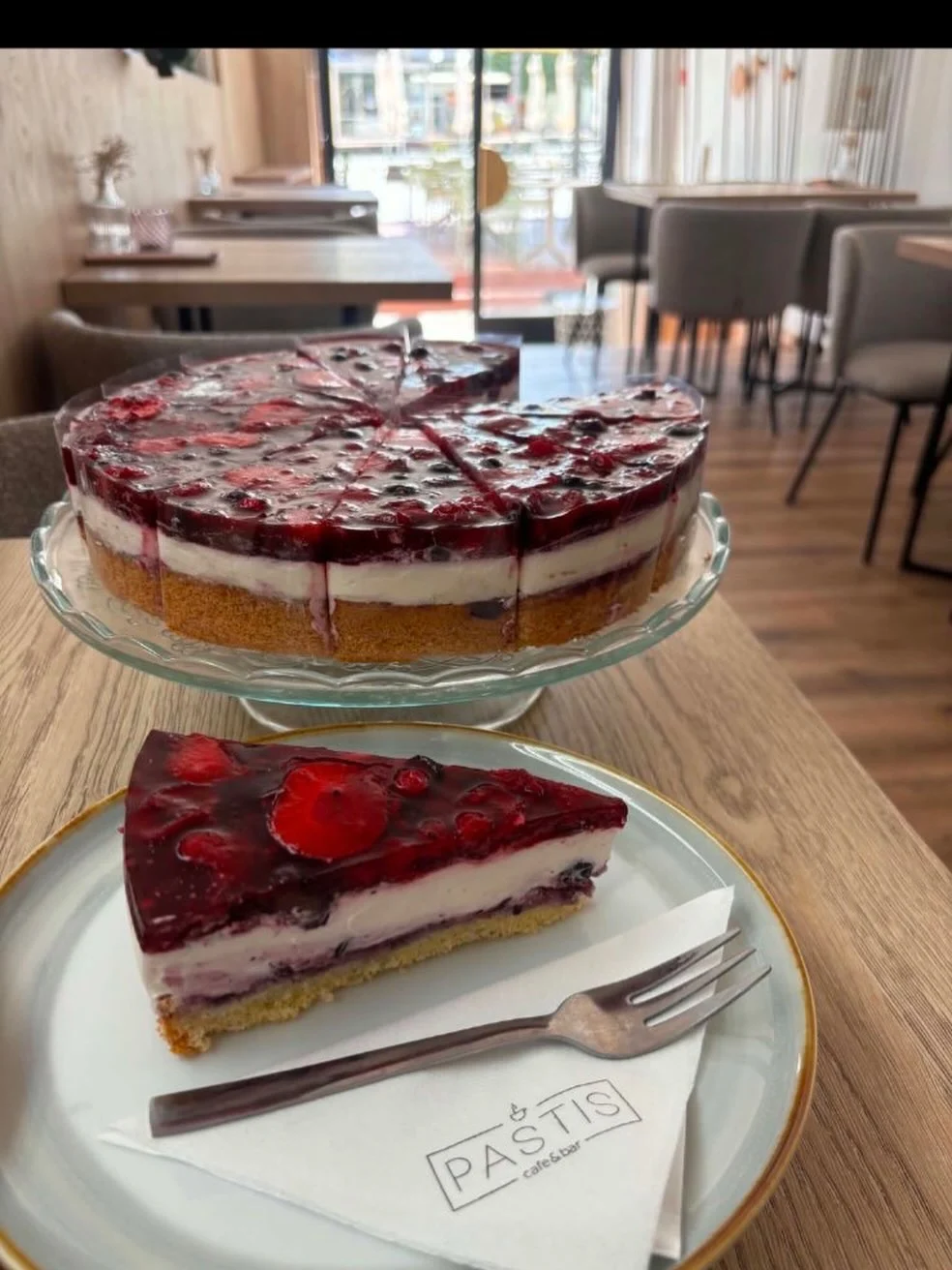 Malinový cheesecake na tanieri, v pozadí celá torta