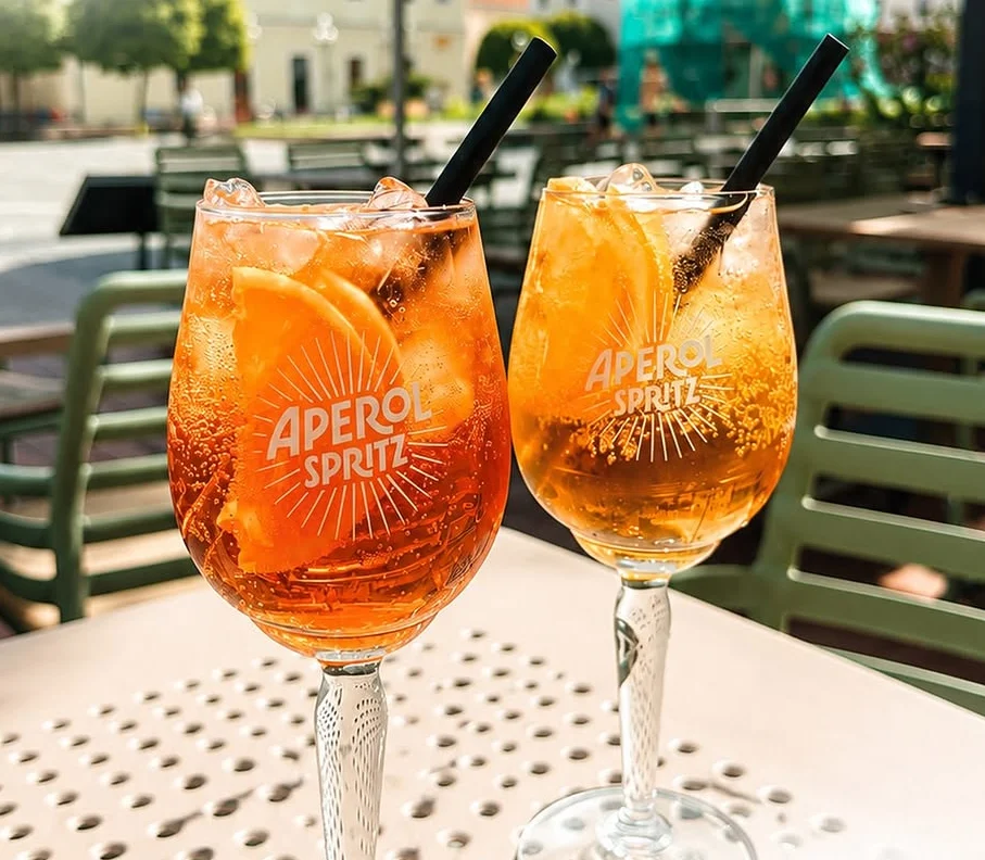 Dva poháre Aperol Spritz na terase s výhľadom na Trojičné námestie